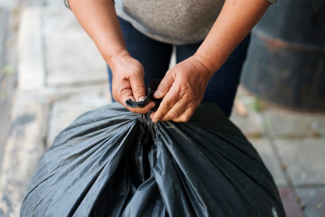 Man tries to tie a trash bag for recycle