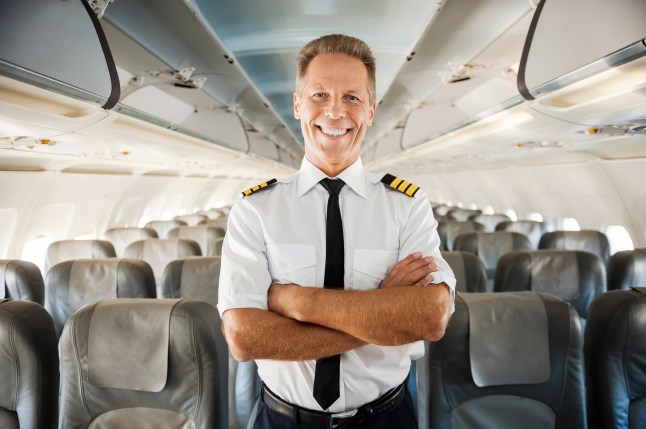 Pilot stands in the middle of plane aisle.