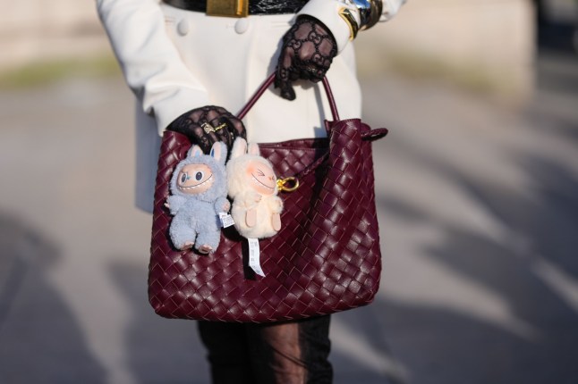 A labubu accessory on a burgundy bag.